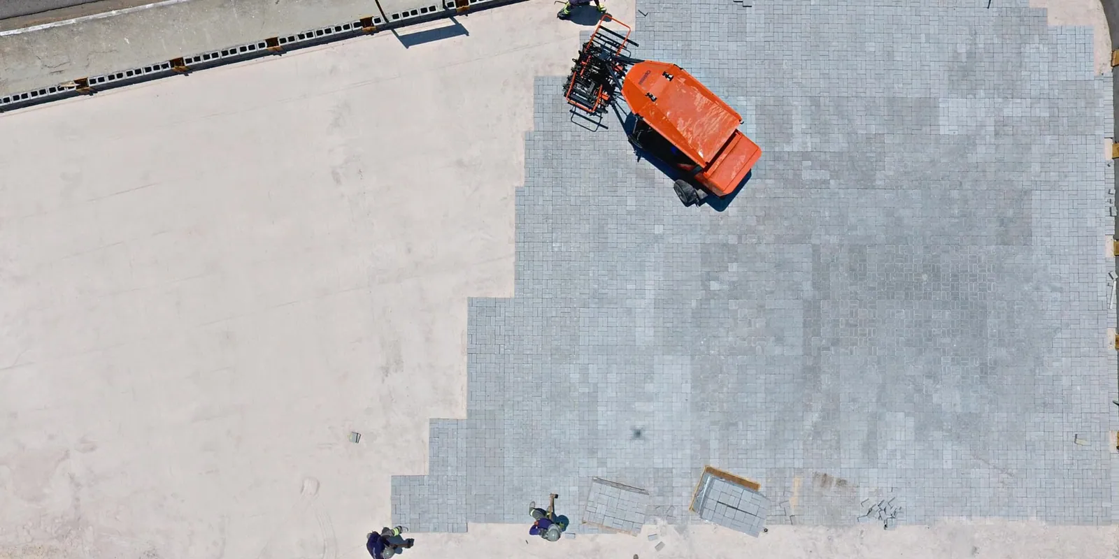 Vista aérea de pavimentação com peças de concreto da VITNO e equipamento em obra